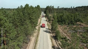 Firefighters trucks and tracked all terrain vehicles driving on forest road aerial view. Red firetrucks inspecting summer forest for wildfires. Emergency firemen transport rescue equipment from above