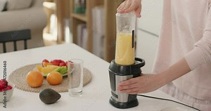 Happy young woman making juice at home,4K
