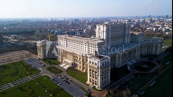 High angle drone footage of the Palace of the parliament in Bucharest Romania. Constitution Square seen from above on a sunny green day. Ceausescu's palace seen from above. Flyover shot