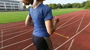 Young sporty woman jogging in sports wear on stadion at sunset. 60fps 4K video
