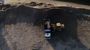 Download USA, California - May 20, 2022. excavator digging and loading sand into dump truck at river bank. Scene. Heavy machinery working at sand quarry.
