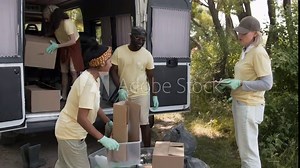 Full tilt-up shot of multiethnic team of cheerful young eco volunteers loading containers full of recycled rubbish into minivan trunk, event organizer checking report, while wrapping up forest cleanup Stock Video