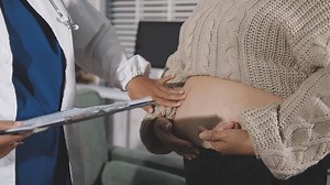 Download A doctor examining a pregnant woman's stomach for free