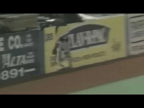 Rodney McCray crashes through the outfield fence