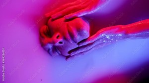 a pretty female face with lips pumped up by a filler plunges into a bath with a white liquid