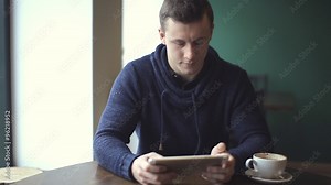 man using tablet computer touchscreen in cafe