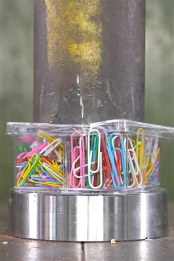 Colorful paper clips get crushed inside plastic box