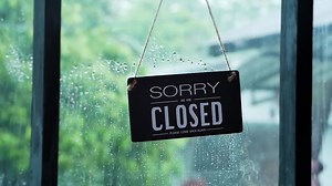 Download A closed sign hanging on the front door of the restaurant swaying on a rainy day for free