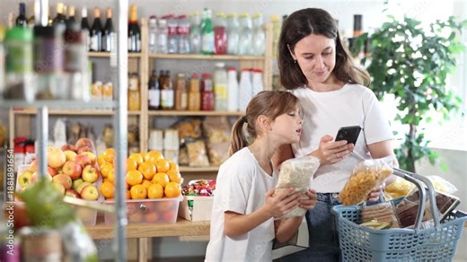 Girl with mother customers at shop scan QR code on cornflakes and oat flakes package using phone camera. They study shelf life, learns calorie content of product using application.