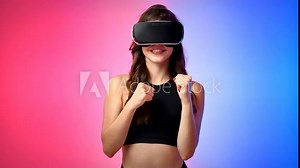 Young smiling woman in a tracksuit in virtual reality VR headset doing boxing exercises in a studio with blue and red background Stock Video