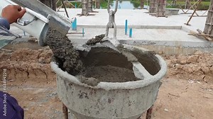 Worker load cement from truck to bucket in construction site.