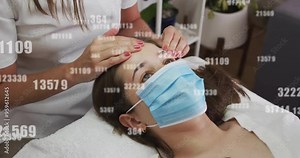Receiving facial treatment, woman wearing mask with numbers overlay animation