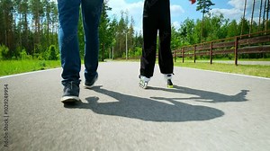 Positive caring father helping cute teenage daughter to ride roller skates in public park. Affectionate dad teaching little girl rollerblading outdoors during weekend.