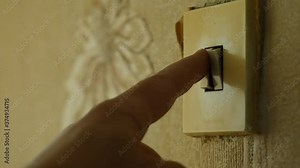 Man hand touches the buttons of light switch. Lamp wall switch. Man turns on or off light in apartment. Fingers press switch keys. Old shabby switch made of plastic. Paper wallpaper. Household items