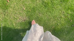 POV: First person view of stepping onto grass, removing flip - flops, turning in a white dress—simple summer moment.