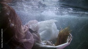 beautiful woman is plunging inside water and floating, underwater shot in pool or lake