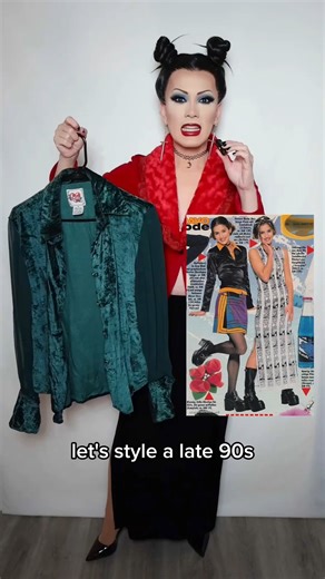 Did you dress like this in the 90s? #90snostalgia #90sfashion #fashionhistory #vintagefashion Video description: Taipei is a drag queen wearing dramatic 90s inspired makeup and space buns hairstyle. She walks her steps to style a late 90s inspired outfit, including a dark green crushed velvet blouse, dark gray flared pants, and chunky black loafers. | Taipeiqueen