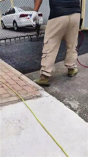 Applying a black asphalt sealant over a grey pavement to restore the surface and look new