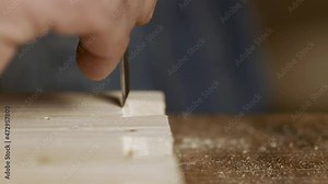 a carpenter cuts out a dovetail on a pine board with a chisel. dovetail joinery is done with a hand tool. woodworker makes an antique spike to connect parts