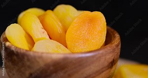 orange dried apricots in a wooden bowl, sweet dried fruits dried pieces of pitted apricots