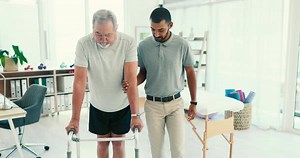 Man, physiotherapy and senior patient with walker in elderly care for walking exercise