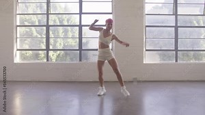 Girl enjoying hip hop moves at light large windows studio. Young hip-hop dancer training dance walk to perform on stage. Happy professional female dancer practicing in white studio, art concept 4K