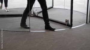 People using automatic revolving glass door entering to a hotel, business, exhibition or shopping center.