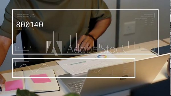 Man writing sticky notes, reaching laptop, HUD overlay updating charts, analyzing finance data