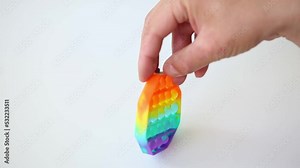 Hands playing with rainbow pop it toy. Plaything for having fun sensory stress relief. Fingers spin on its own axis tool for autists. Helps develop abilities fine motor skills and treatment autism