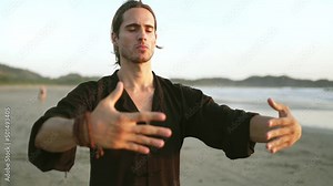 millennial young fit man practice Qi gong, Tai Chi yoga on beach, summer. outdoor activities, social distancing.