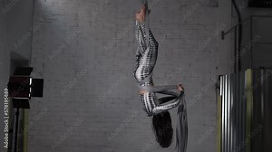 Woman circus artist practicing an aerial silk acrobatic exercise at her studio.Focused aerialist acrobat training new tricks
