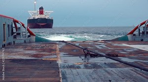 Anchor-handling Tug Supply AHTS vessel during dynamic positioning DP operations near FPSO tanker. Vessel is doing static tow tanker lifting. Ocean tug job.
