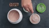 Adding few scoops of chocolate whey protein powder into shaker with...