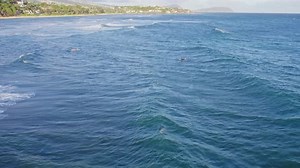 kite boarders and surfers dot the ocean surface as they wait for the perfect wave off the coast of O
