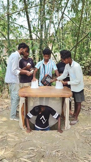The boy is standing under the table, duping people and swindling money.