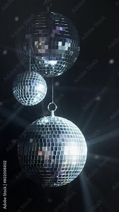 Vertical video. Disco ball with rotating reflected moving rays. Isolated disco ball on black background. Close-up. Mirror ball indoors.