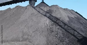 View extraction of black coal at mine on sunny day in outdoors. World mining of natural resources from earth bowels. Huge pile of fossil charcoal under blue sky. Solid fuel carbon production. 4k