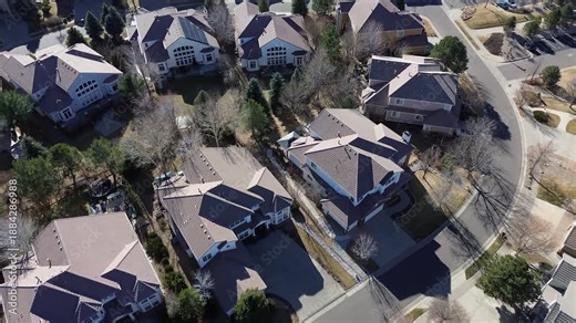 Beige and gray rooftops near South Zeno Way form a grid-like pattern along landscaped curve. Suburban home with solar panels, leafless trees and soft shadows winter scene, Aurora, Colorado