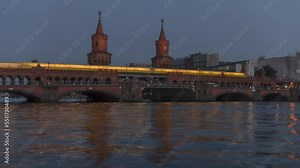Evening Berlin time lapse. Oberbaumbrücke (Oberbaum Bridge) over Spree River that links Kreuzberg and Friedrichshain districts, Kreuzberg district. A subway train passes over the bridge. Germany.