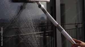 Rubber squeegee cleans a soaped window.