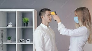 Doctor measures the patient's temperature with a non-contact infrared thermometer. Patient's visit to the doctor