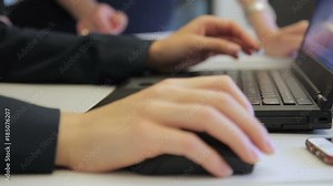 Close-up of female hands in suit work with mouse over laptop. At desktop employees lead pointer over monitor screen while working on database.