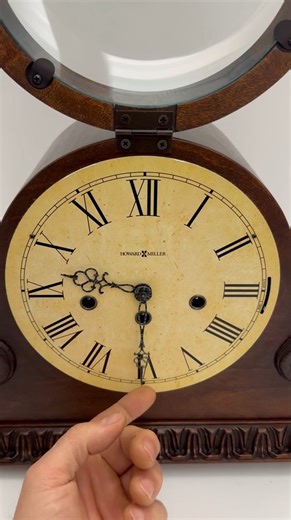 Used Howard Miller Newley Mantel Clock (630-198) * NEW KIENINGER MOVEMENT * 2-YEAR WARRANTY * Dimensions: 11.5” H x 22” W x 6.75” D * Furniture Trend Designs Collection by Howard Furniture * Americana Cherry finish * Made from select hardwoods and veneers * Classic tambour silhouette with beautiful details give this mantel clock a unique presence in any room * Base features a decorative molding that wraps around three sides of the clock * Detailed, bookmatched leaf and rosette patterns flank the