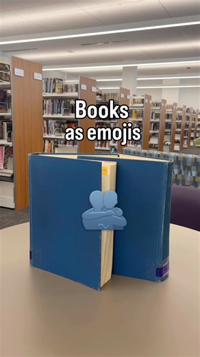 Helen Plum Library on Instagram: "🤓 ❤️ 📚 Just over here making art. 👨‍🎨 For funsies, let us know what book you’re reading below using only emojis. Video description: books being positioned to mimic various emojis. Two blue books hug each other to form the hugging emoji. A camping book opens like a tent, and a tree book is placed behind it to form the camping emoji. Green, red, and blue books about finance line up to make a bar graph emoji. An atlas opens up to make the map emoji. A blue, red