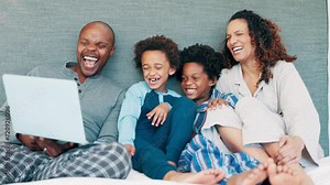 Black family, bed and laptop with movie, smile and streaming series in the morning. Laughing, computer and happy father with children and mother together with care, meme and web video at home online