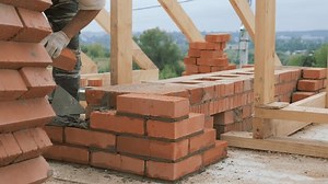 Laying out a brick chimney chimney of a private wooden house. Construction work of a bricklayer. Refractory mortar and red brick. High-altitude work.