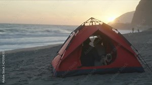 Couple sit in tent and enjoy view at a beach. Traveling on trailer and camping by West Coast of California. Lovely moments.