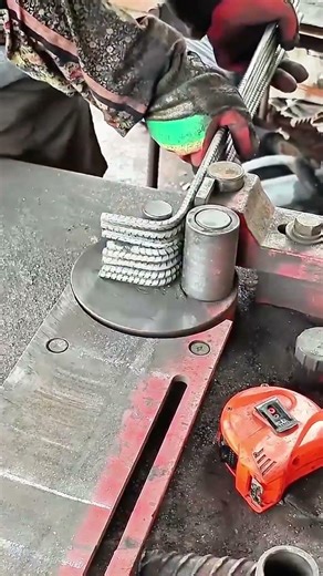 Gloved hands guide rebar—disc turns, steel bends with practiced torque and industrial rhythm