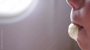 Closeup view of cute little kid chewing gum and blowing bubbles while having flight by airplane. Real time full hd video footage.