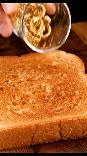 New generation on Instagram: "Ultra-realistic macro food ASMR scene with strict visual-identity enforcement and locked composition. Define the object ONLY by name: (OBJECT).The Al must treat this object's real-world color, hue, tone, and surface identity as immutable and dominant at all times. Under no circumstances may the color shift toward butter, cream, yellow, beige, white, or dairy-like tones.A single thick slice of toasted bread lies perfectly flat and centered on a dark wooden cutting bo